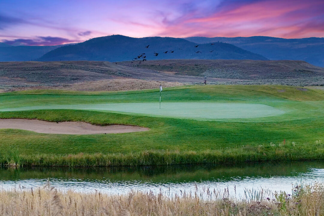 Grand Elk Golf Club, water in foreground, mountains and colorful skies in background