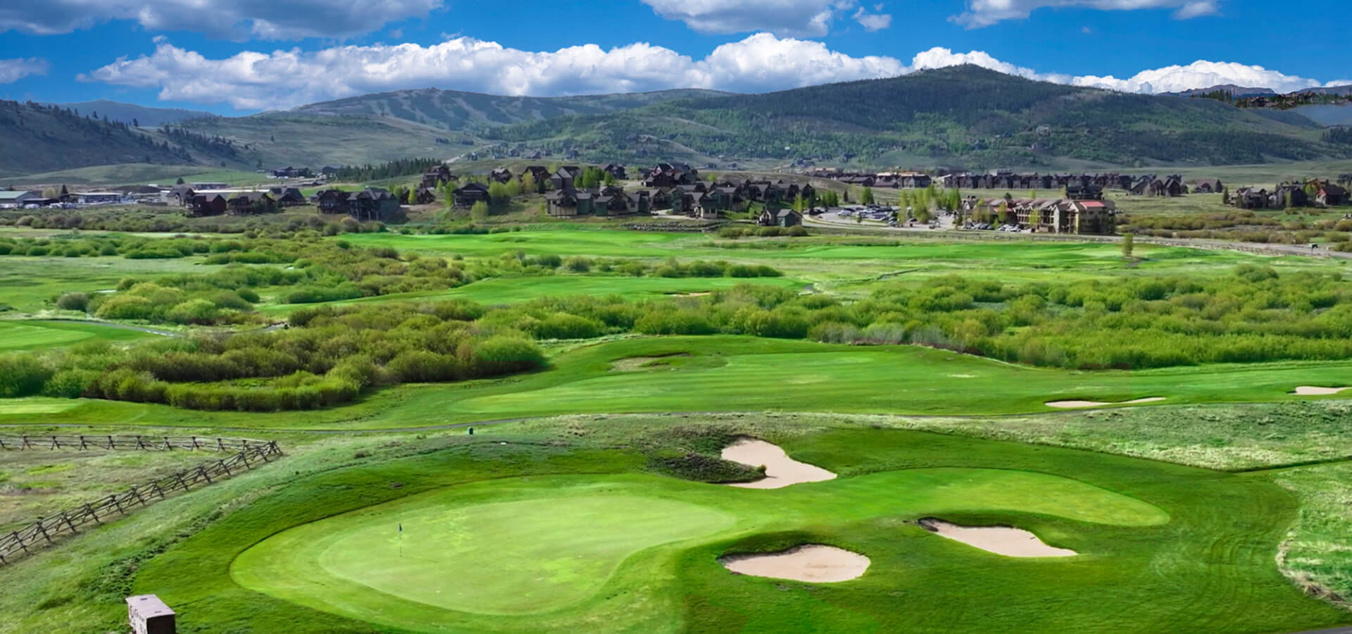 Grand Elk Golf Club with mountains in background, blue sky, white clouds<br />
